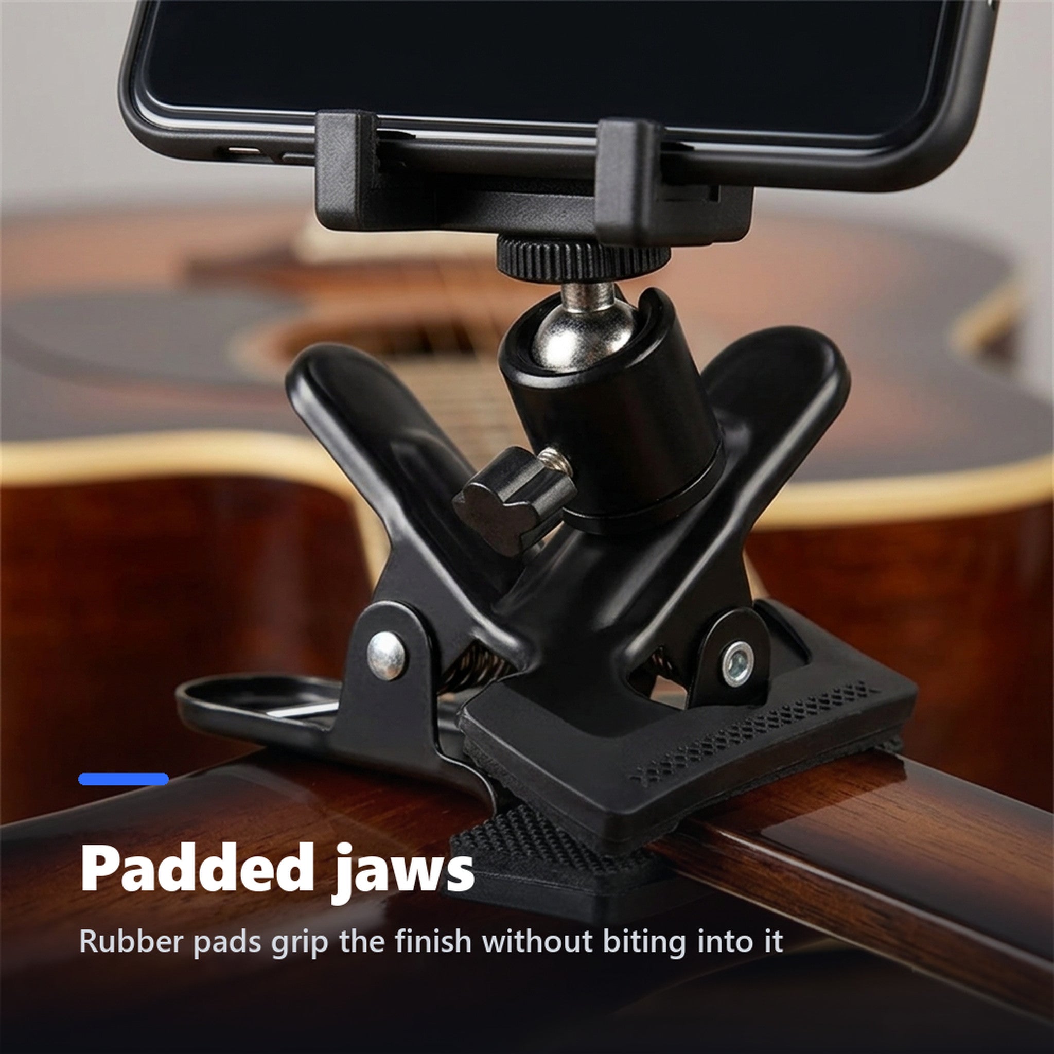 Close-up of rubber padded jaws gripping a guitar headstock